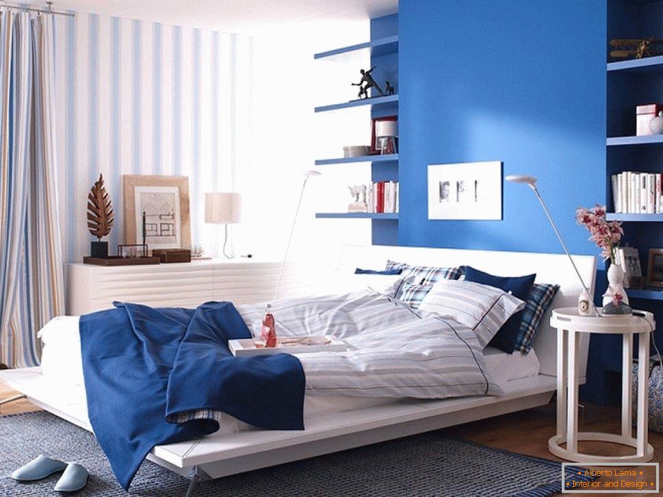 Modrá zeď v ložnici kombinovaná s pruhovanou tapetou