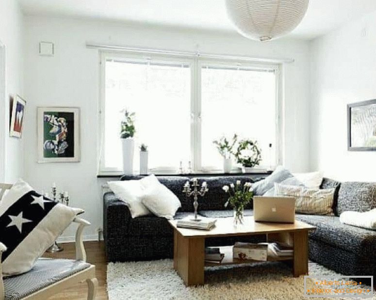 Malý obývací pokoj v bílém s tmavou rohovou pohovkou a oknem