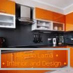 Plochá černá zástěra v oranžové kuchyni