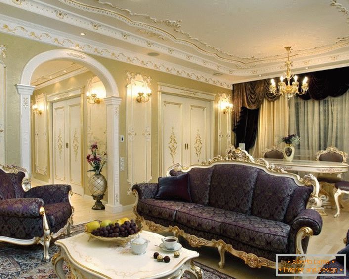 Příklad kompetentní kombinace barev v dekoraci v barokním stylu. Čalounický nábytek, lambreky a koberec, vyráběné v lilach, jsou kombinovány i s hrozny na stole a květinami. Tenký záměr návrhu.