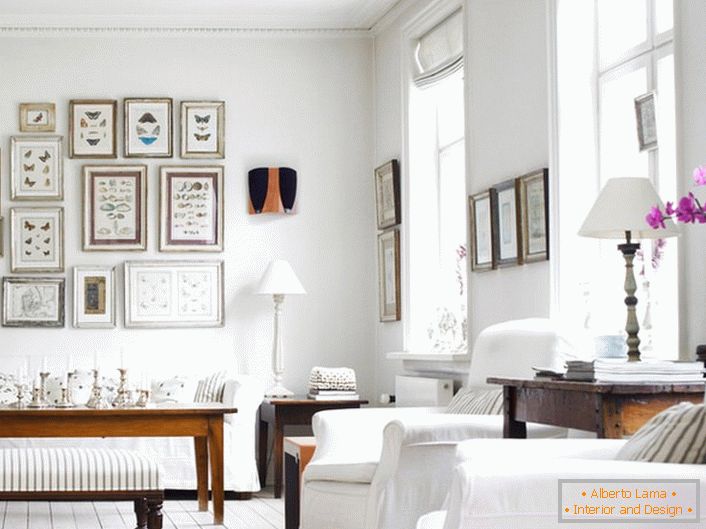 Útulný obývací pokoj ve skandinávském stylu je vyroben v bílé barvě. Je zajímavé zdobit stěnu rámy různých velikostí.