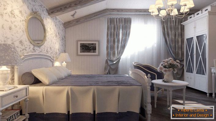 Pokoj ve venkovském stylu je vyroben v tlumených modrých tónech. Stěna na hlavě postele je pokryta tapetami s květinovým vzorem.