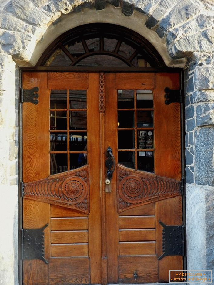Dveře v secesním stylu zdobí přední dveře venkovské chatky s fasádou z přírodního kamene. 
