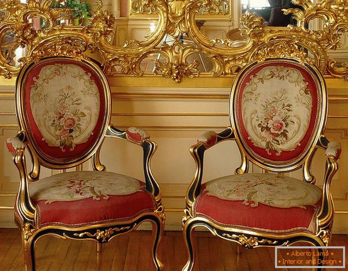 Otevřená štuková ozdoba zlaté barvy na zrcadle a židle s červeným měkkým čalouněním - jasné barokní představitele.