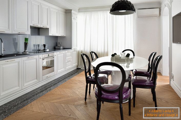Bílá interiérová kuchyně s diakritikou tmavě šedé v eklektickém stylu. Zajímavé židle s průhlednými zády a fialovým měkkým čalouněním.