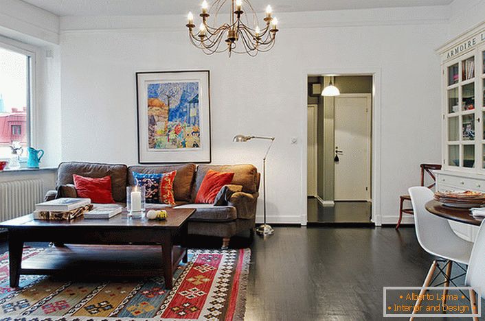 Stylový pokoj pro hosty v typickém městském apartmánu je zařízený světlými polštáři na pohovce a koberci. 