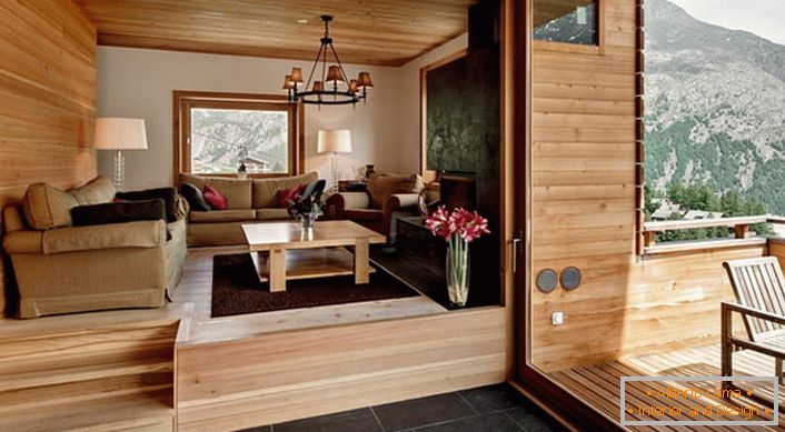 Podkroví vily s přístupem na verandu je vyzdobeno ve stylu chaty. Barva lehkého dřeva vypadá ziskově v kombinaci s tmavě hnědou dlaždicí.