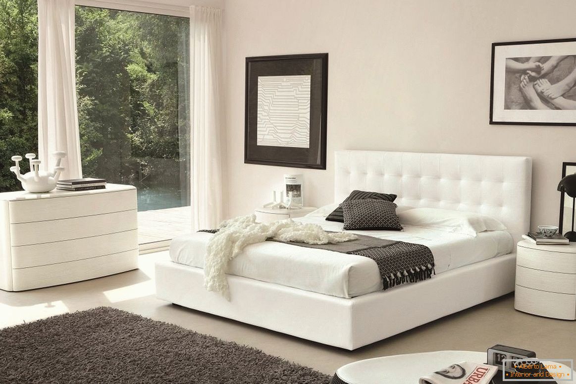 Bílá postel, zásuvková skříň a noční stolek v ložnici