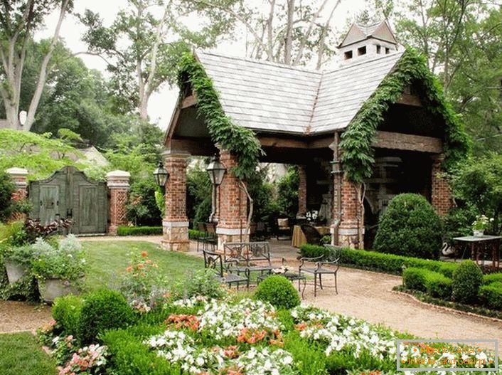 Elegantní jednoduchost otevřeného altánu ve stylu chaty vypadá organicky v luxusní, útulné zahradě. 