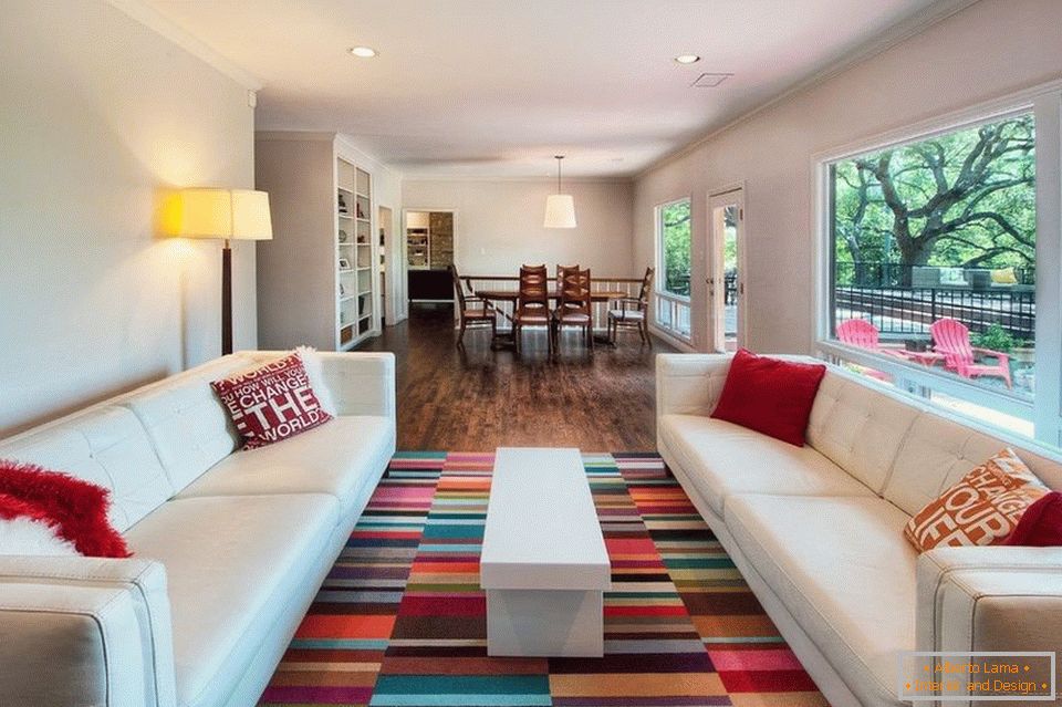 Obývací pokoj s bílými pohovkami a barevným kobercem