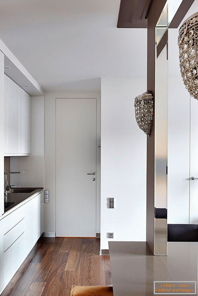 Bílý kuchyňský nábytek, bílé vchodové dveře a krásné dřevěné parkety