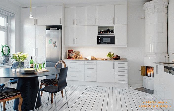 Kachlový krb, vyrobený z bílé keramické dlažby, organicky zapadá do interiéru kuchyně ve skandinávském stylu.