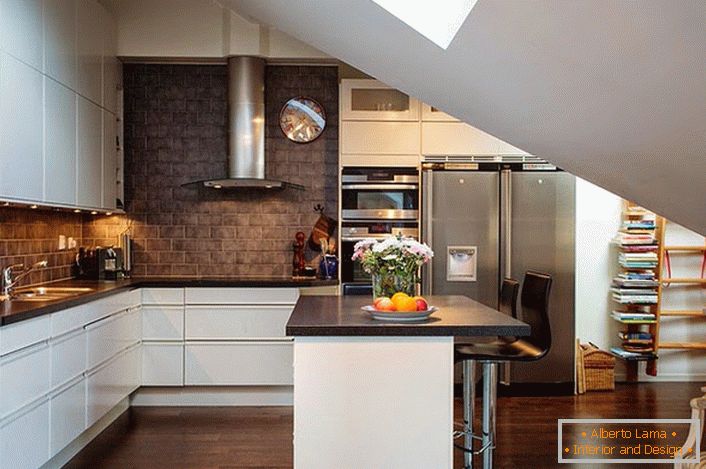 Kuchyně v podkroví je vyzdobena ve skandinávském stylu. Bílá kuchyňská sada vypadá dobře na pozadí stěn tmavých cihel. 