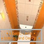 Kombinace bílé a oranžové dlažby v designu toalety