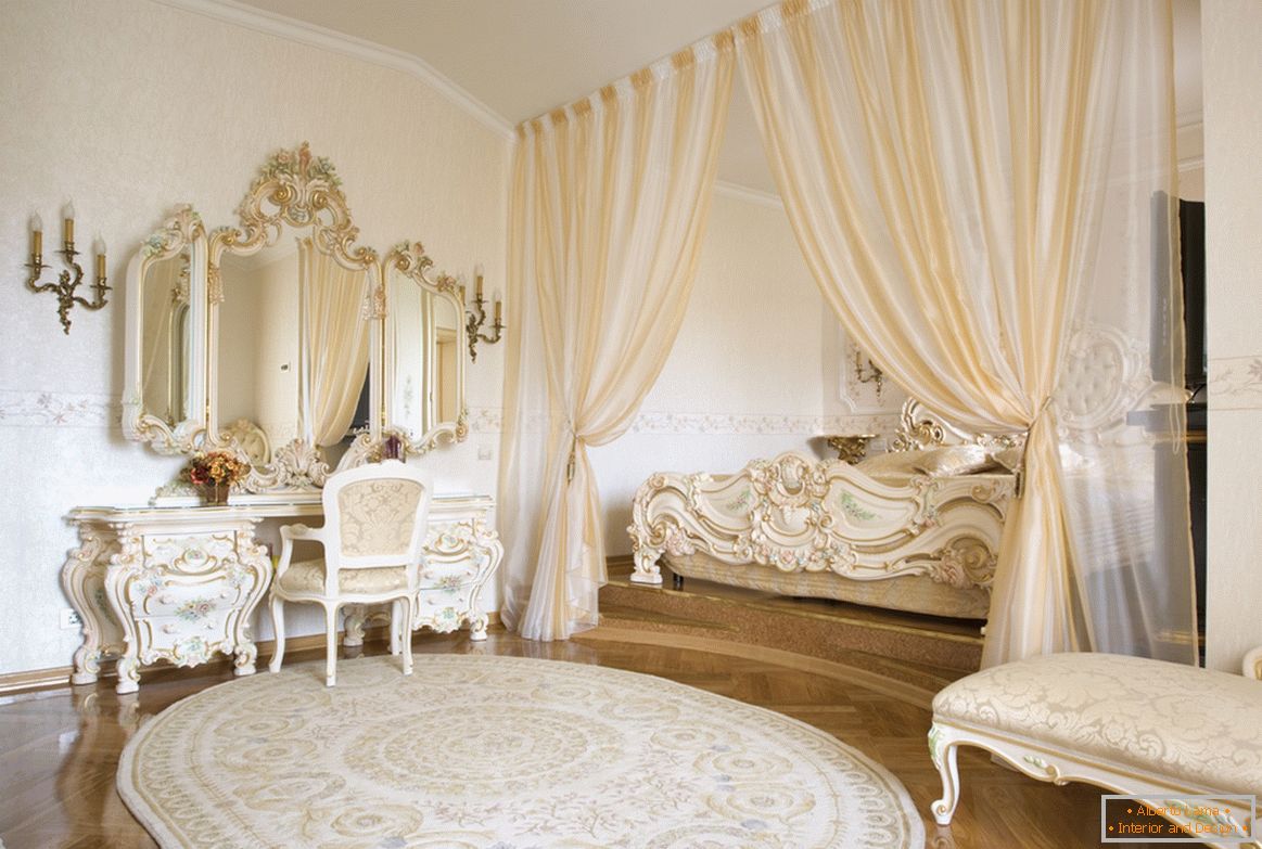 Rámovací zrcadla a dekorativní prvky nábytku jsou vyrobeny v jednom stylu s použitím zlata. Pro úsporu místa je postel ukrytá v výklenku ohraničeném záclonami.