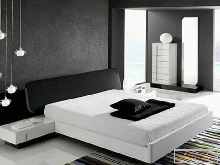 Stěna v horní části postele zdobená šedou matovou vložkou v souladu se stylem hi-tech je v souladu s lesklou bílou podlahou.