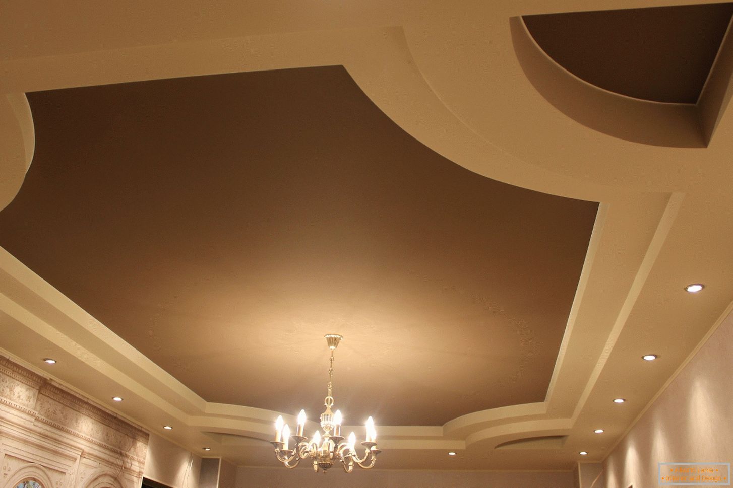 Matné roztažitelné PVC stropy pro pokoj pro hosty ve venkovském domě. Víceúrovňová konstrukce stropů vypadá zajímavě ve světle béžové a tmavě hnědé barvě.