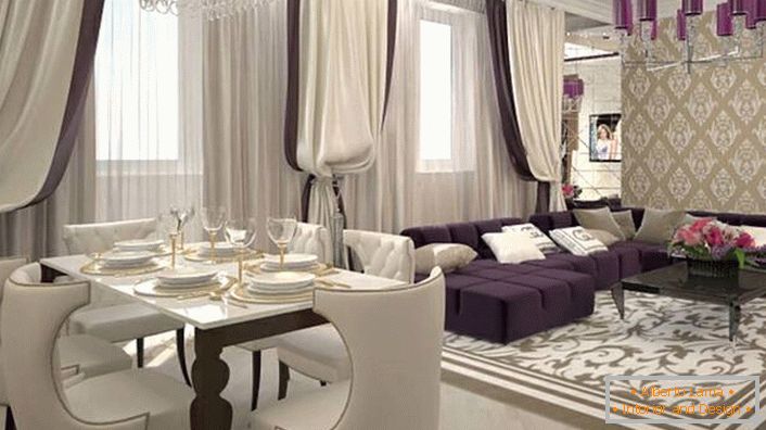Těžké záclony na oknech v kombinaci s měkkým nábytkem z bílého lila se spojují, aby se vytvořil interiér ve stylu art deco. V souladu se stylem je také vybráno osvětlení. Stropní lustr je zdoben stejnými lesklými odstíny tmavě fialové.