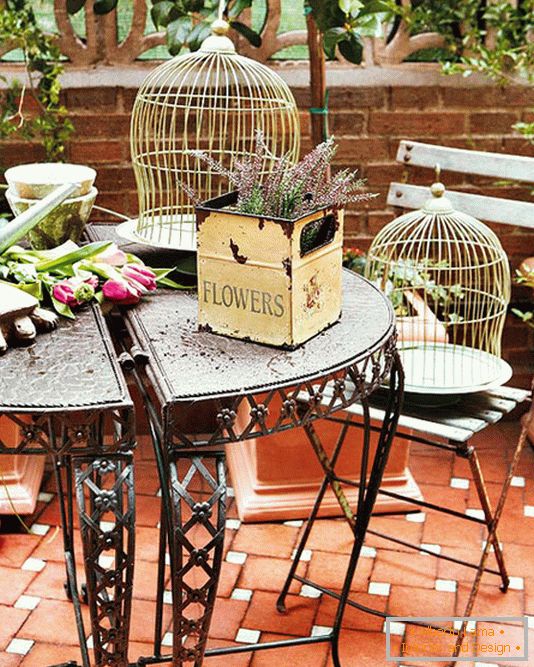 Kované stoly, krabice s květy a klece pro ptáky
