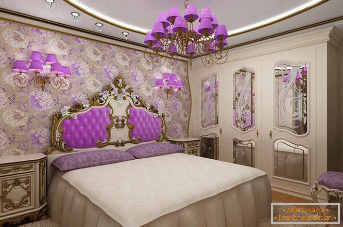 Elegantní barokní ložnice se zajímavým přízvukem na osvětlení. Lustrové a noční lampičky se stejnými fialovými odstíny harmonicky kombinované s čalouněním opěradla na hlavě postele.