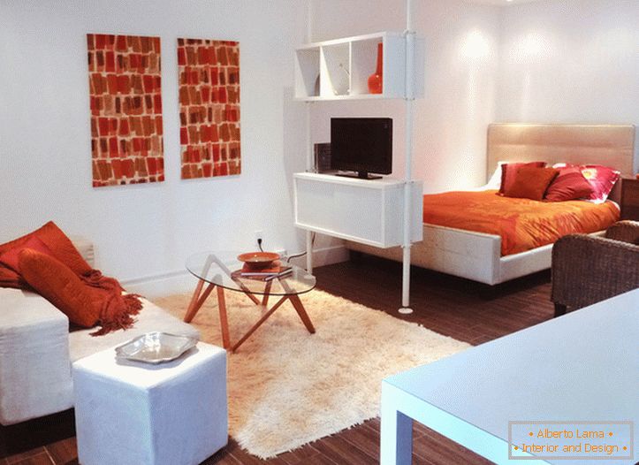 Interiér bílého studiového bytu s oranžovými akcenty